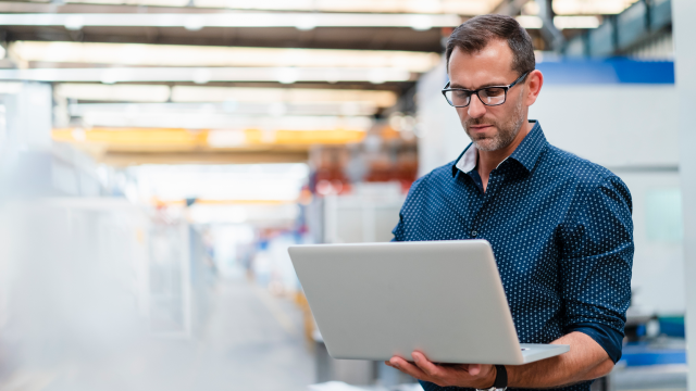 A person holding and viewing a laptop